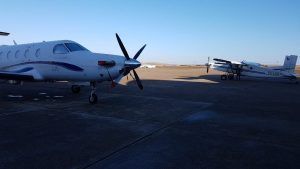 Dos pequeñas avionetas blancas están estacionadas en la pista de un aeropuerto bajo un cielo azul claro, listas para una emocionante aventura de "Salto en paracaídas con Skydive Madrid". - ForTwo - Planes para parejas