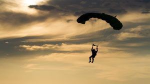 Silueta de una persona disfrutando de un salto en paracaídas con Skydive Madrid contra un cielo nublado al atardecer. - ForTwo - Planes para parejas