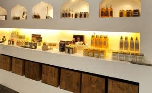 Los estantes con tarros y botellas de miel brillan bajo una cálida iluminación amarilla, haciendo eco del ambiente sereno del Hammam Ritual de los Sultanes en Rituels d'Orient Barcelona, invitando a pensamientos de tranquilidad. - ForTwo - Planes para parejas