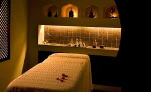 La sala de masajes, tenuemente iluminada, que evoca el ambiente de un Hammam en Rituels d'Orient Barcelona, cuenta con una mesa elegantemente adornada y una iluminación suave, ideal para la relajación y el rejuvenecimiento. - ForTwo - Planes para parejas