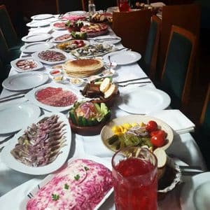 Restaurante La Alacena de Francis en Málaga exhibe una larga mesa de comedor con una variedad de platos, que incluyen carnes suculentas, verduras frescas y una bebida roja vibrante en una copa elegante. - ForTwo - Planes para parejas