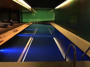 La Sensación de Serenidad del Spa Mandarin Oriental de Barcelona cuenta con una lujosa piscina cubierta con una serena iluminación azul, una terraza de madera, elegantes paredes de cristal y elegantes escalones que conducen al agua para una tranquila experiencia similar a la de un spa. - ForTwo - Planes para parejas