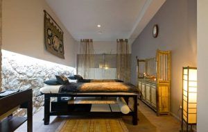 Un acogedor dormitorio con dos camas individuales, iluminación tenue y tapices decorativos ofrece un ambiente cálido en Barcelona. Al igual que la experiencia de Vinoterapia en el Ambrosia Urban Spa, combina a la perfección comodidad y estilo para un retiro de spa urbano. - ForTwo - Planes para parejas