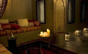 Cómoda habitación con iluminación tenue, asientos acolchados, velas de mesa y una decoración de estilo marroquí inspirada en el Hammam Ritual de los Sultanes de Rituels d'Orient Barcelona. - ForTwo - Planes para parejas
