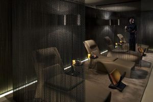 En la tranquila atmósfera del Spa Mandarin Oriental de Barcelona, una suave iluminación ilumina los lujosos sillones reclinables y las cortinas de cadena. Un miembro del personal ofrece elegantemente bebidas en una bandeja, creando un oasis de calma llamado Sensación de serenidad. - ForTwo - Planes para parejas
