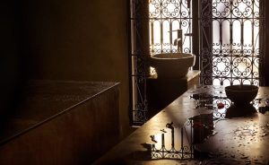 En una habitación tenuemente iluminada con rejas de hierro ornamentadas, que recuerda al Hammam Ritual de los Sultanes en Rituels d'Orient de Barcelona, el agua se derrama sobre la encimera junto al fregadero y los lavabos. Un aire tranquilo llena este espacio sereno, evocando su esencia. - ForTwo - Planes para parejas