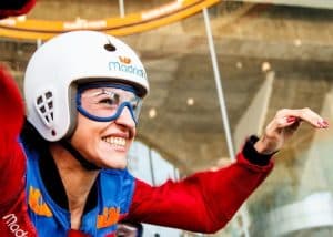 Una persona sonríe mientras se viste con el equipo de paracaidismo para una emocionante sesión de Paracaidismo indoor en el túnel de viento Madrid Fly, completa con casco y gafas. - ForTwo - Planes para parejas