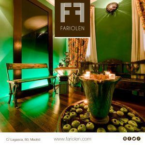 Una acogedora sala con iluminación verde, bancos de madera, manzanas decorativas y velas alrededor de un gran espejo se ve realzada por el logo de Fariolen en este spa madrileño inspirado en la estética japonesa. - ForTwo - Planes para parejas