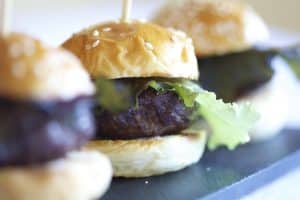 Primer plano de una hamburguesa de ternera con lechuga sobre un pan de sésamo, colocada sobre una tabla de pizarra, que recuerda el arte de "Spa y masaje a lo japonés + menú de tapas en Madrid". - ForTwo - Planes para parejas