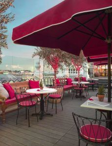 El Restaurante Ático del Hotel The Principal Madrid cuenta con una encantadora cafetería al aire libre con sombrillas rojas y asientos, que ofrece impresionantes vistas al mar al atardecer. - ForTwo - Planes para parejas