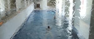 Vista borrosa de una piscina cubierta en el Circuito de Hidroterapia en el Spa de La Cala Golf Málaga, que muestra a un nadador visto a través de un cristal con gotas de agua. - ForTwo - Planes para parejas