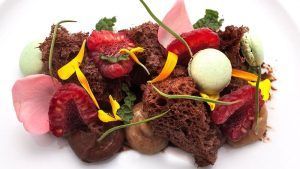 En el Restaurante La Rotonda del Hotel Westin Palace Madrid, disfrute de un postre de lujo con bizcocho de chocolate, frambuesas, macarons y flores comestibles bellamente presentados en su plato. - ForTwo - Planes para parejas