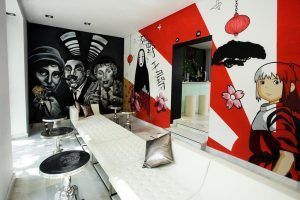 Esta vibrante sala del Hotel Dormirdcine Madrid exhibe murales de arte moderno con diseños abstractos y personajes de dibujos animados, combinados con cómodos sofás blancos y elegantes mesas redondas. - ForTwo - Planes para parejas
