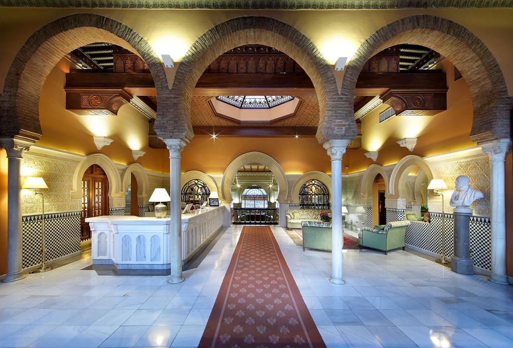 El vestíbulo del hotel, similar al del Hotel Alhambra Palace Granada, exhibe techos de ladrillo arqueados, una recepción de buen gusto, una decoración sofisticada y una alfombra roja estampada que guía elegantemente a uno a través de la zona. - ForTwo - Planes para parejas