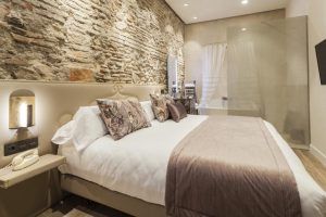 Experimente un santuario moderno en el Hotel Palacete de Álamos Málaga, donde podrá relajarse en una elegante habitación con una pared de ladrillo a la vista, una cama grande, iluminación suave y una zona de bañera con paredes de vidrio para relajarse. - ForTwo - Planes para parejas