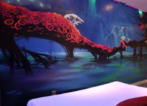 Un colorido mural en el Hotel Santo Domingo Madrid muestra formaciones surrealistas similares a corales rojos sobre el agua, vistas desde arriba de un lecho blanco prístino. - ForTwo - Planes para parejas