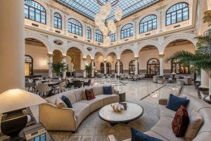 El lujoso vestíbulo del Gran Hotel Miramar Málaga cuenta con elegantes sofás, altos techos abovedados, brillantes lámparas de araña y exquisitos suelos de mármol. - ForTwo - Planes para parejas