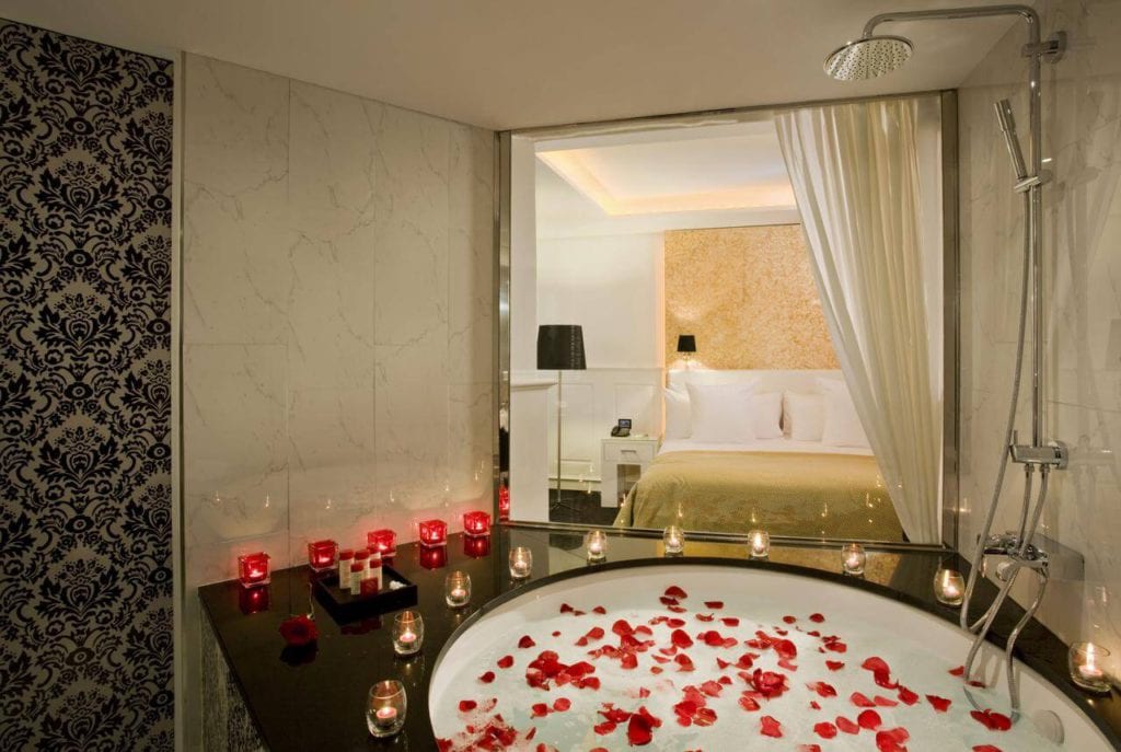 Disfrute de una relajación de lujo en el Hotel Gran Meliá Colón Sevilla con un baño de pétalos de rosa y un ambiente a la luz de las velas. Disfrute de una decoración elegante que se integra a la perfección con las vistas de su dormitorio a través de una elegante cortina divisoria, todo ello enclavado en el corazón de Sevilla. - ForTwo - Planes para parejas