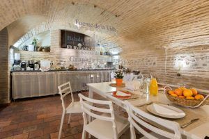 Disfrute del encanto del acogedor comedor del Hotel Boutique Gar Anat Granada con una mesa blanca, sillas, un delicioso desayuno, jugo de naranja natural y un techo de ladrillos a la vista en Granada para una estadía inolvidable. - ForTwo - Planes para parejas