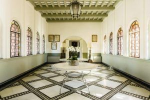 El Hotel Castillo de Santa Catalina Málaga cuenta con un elegante vestíbulo con suelo de mármol ajedrezado, mesas redondas con orquídeas, ventanas arqueadas y una llamativa lámpara colgante. - ForTwo - Planes para parejas