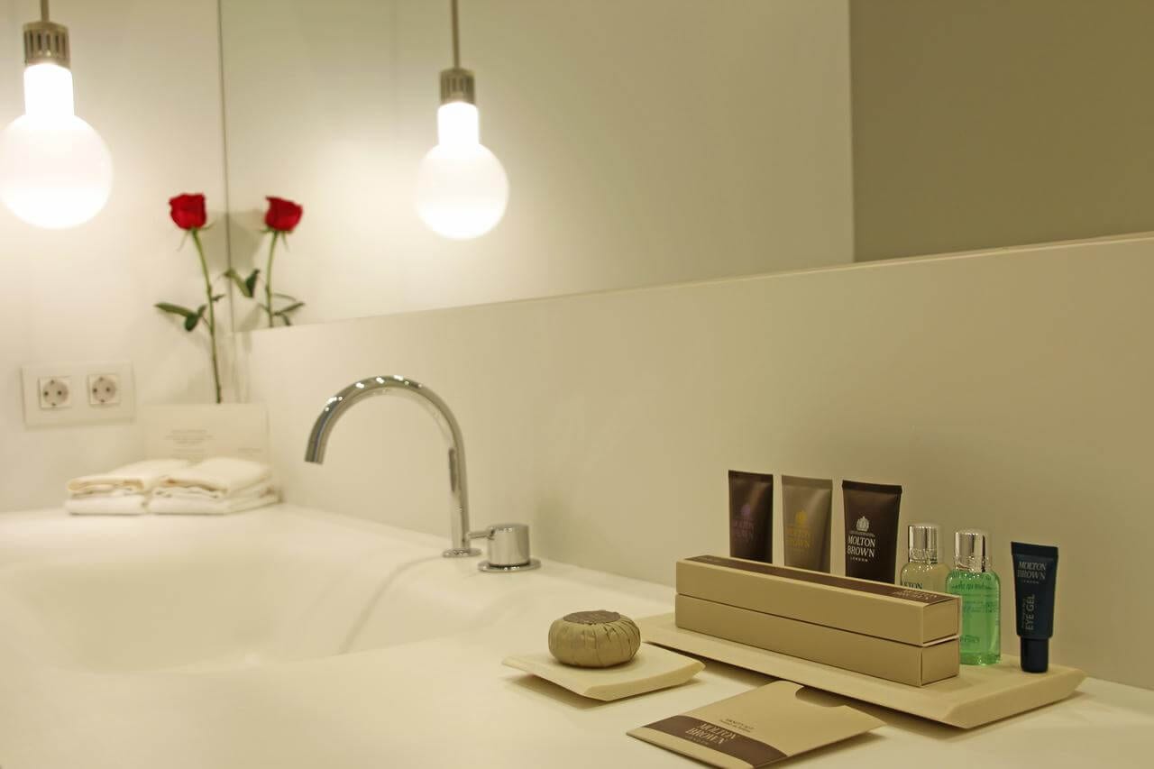 El Hotel Mercer de Sevilla cuenta con un tranquilo baño con una bombilla incandescente, rosas rojas, lujosas toallas y artículos de tocador de primera calidad en el mostrador. - ForTwo - Planes para parejas