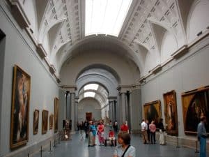 En una espaciosa galería del museo con altos techos e iluminación brillante, los visitantes admiran pinturas durante una Visita guiada por el Museo del Prado. - ForTwo - Planes para parejas
