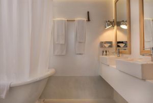 Experimente la tranquilidad en el Hotel 7 Islas Madrid con un baño minimalista con una lujosa bañera blanca, toallero, lavabos dobles y espejos. Disfrute de una iluminación suave y tonos neutros para una escapada serena en el corazón de la ciudad. - ForTwo - Planes para parejas