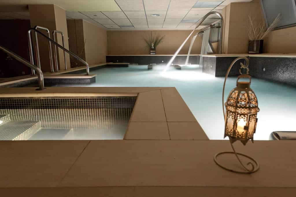 Kumaras Spa (Umbrete) ofrece un oasis interior con una piscina suavemente iluminada, linternas relajantes y chorros de agua vigorizantes, todo ello parte de su "Circuito spa con Masaje e infusión o zumo", creando el ambiente tranquilo perfecto para una experiencia relajante. - ForTwo - Planes para parejas