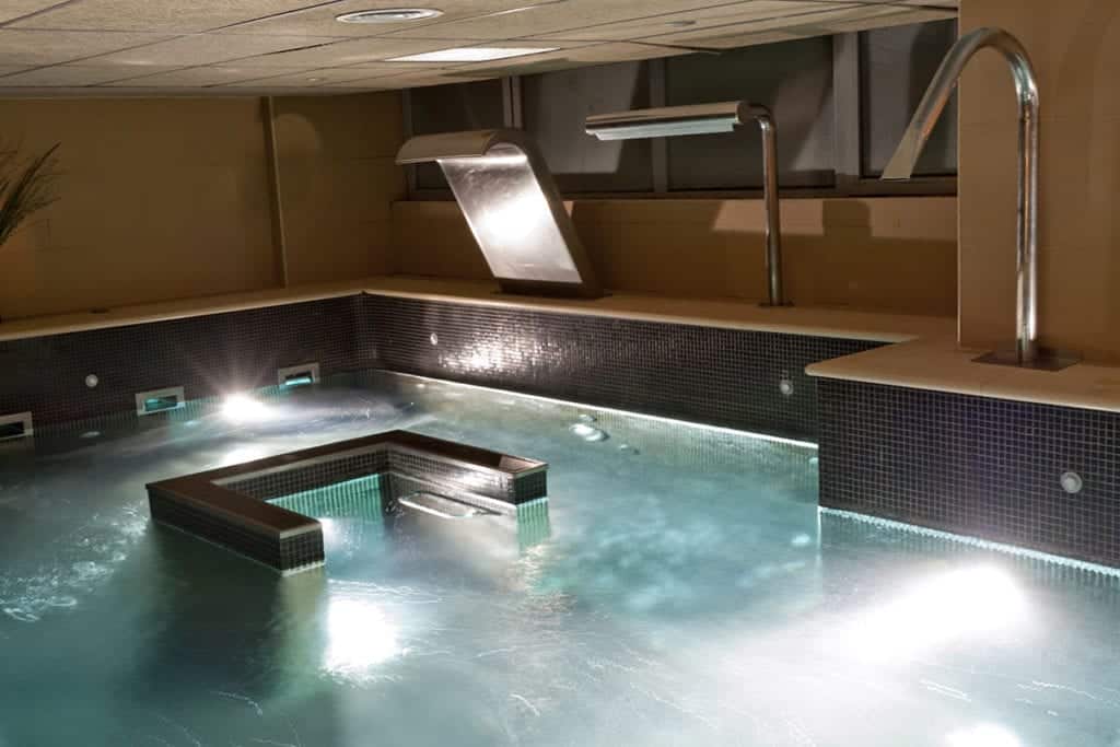 Relájese en el Kumaras Spa en Umbrete. Deléitese en la cautivadora piscina interior con encantadores juegos de agua en elegantes paredes de azulejos. Experimente la relajación con el Circuito Spa con Masaje e Infusión o Zumo para un retiro inolvidable. - ForTwo - Planes para parejas