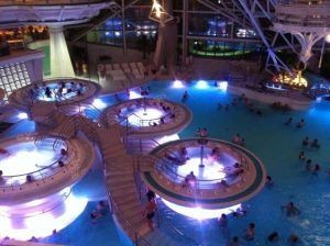 La Entrada al spa de Caldea en Andorra se transforma en un oasis de serenidad por la noche, donde los huéspedes pueden disfrutar de la piscina cubierta, los jacuzzis y los pasillos iluminados para vivir una experiencia típicamente tranquila. - ForTwo - Planes para parejas