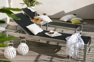 Dos sillones negros con almohadas blancas descansan sobre una terraza de madera entre exuberantes plantas y linternas decorativas, reflejando la serena elegancia de Eric Vökel Boutique Apartments. - ForTwo - Planes para parejas