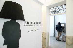 Un hombre se encuentra en un cajero automático junto al elegante cartel de Eric Vökel Boutique Apartments en Madrid. - ForTwo - Planes para parejas