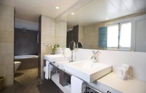 Este moderno baño, con dos lavabos, un gran espejo y zonas de ducha y bañera separadas, refleja el estilo del Hotel Hospes Las Casas del Rey de Baeza (Sevilla) y está iluminado con luz natural y cenital. - ForTwo - Planes para parejas