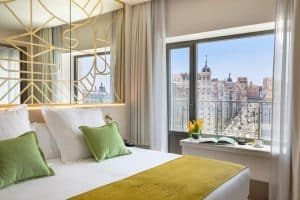 Alójese en el Hotel Barceló Torre de Madrid, con habitaciones con detalles en verde, una cama grande y un cabecero decorativo que ofrecen impresionantes vistas a la ciudad. Ideal para quienes buscan elegancia en el corazón de Madrid. - ForTwo - Planes para parejas