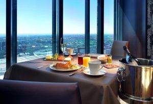 En el Hotel Eurostars Madrid Tower, disfrute de una deliciosa mesa de desayuno junto a la ventana con champán, zumo y deliciosa comida mientras admira las impresionantes vistas del paisaje urbano y el cielo azul. - ForTwo - Planes para parejas