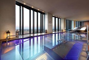 Descubra la lujosa piscina infinita cubierta del Hotel Eurostars Madrid Tower, donde la decoración moderna se fusiona con las vistas panorámicas de la ciudad. Relájese en las cómodas tumbonas y disfrute de una experiencia verdaderamente opulenta. - ForTwo - Planes para parejas