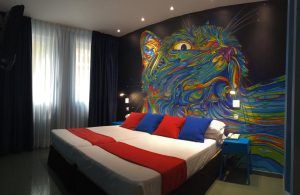 El Hotel Indiana (Madrid) ofrece habitaciones con vibrantes murales abstractos de gatos, almohadas rojas y azules y alfombras para crear un ambiente animado y a la vez acogedor. - ForTwo - Planes para parejas