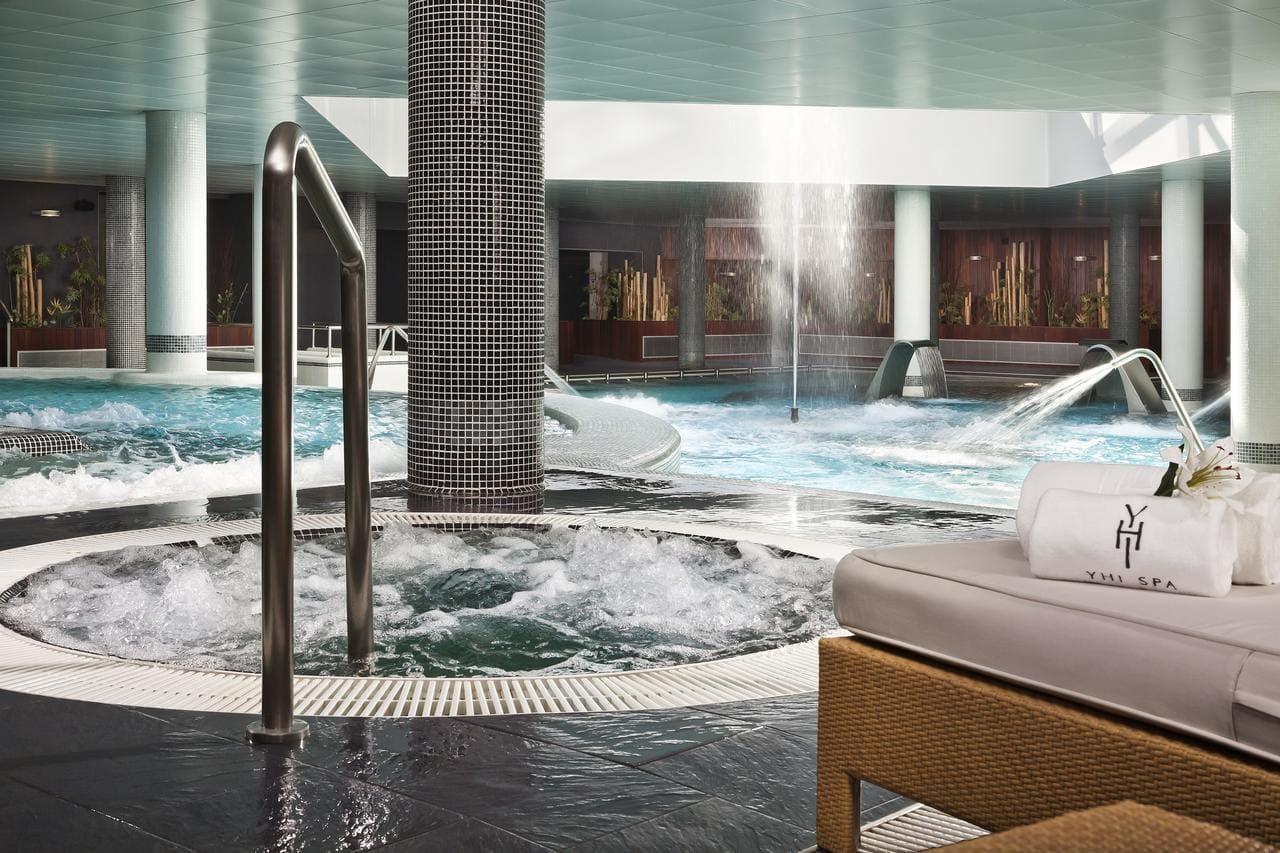 En el Hotel Meliá Sol y Nieve en Sierra Nevada (Granada), nuestro spa interior ofrece bañera de hidromasaje, cascada, tumbonas y una toalla YHI SPA expuesta en medio del hermoso telón de fondo de Sierra Nevada. - ForTwo - Planes para parejas