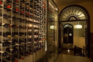 Una moderna bodega de vinos en Granada exhibe estantes montados en la pared y un arco con poca luz, capturando la esencia del Menú Aljibe del Restaurante Alacena de las Monjas. - ForTwo - Planes para parejas
