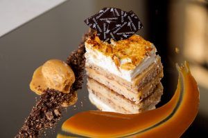 Deléitese con un postre en capas con crema, cobertura de almendras, guarnición de chocolate y caramelo, helado y crumble de chocolate: un final perfecto para su Menú romántico en el restaurante Abades (Ronda). - ForTwo - Planes para parejas