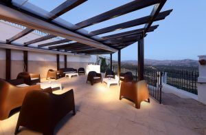 Viva una velada romántica en el restaurante Abades con el Menú romántico, disfrutando de modernas sillas bajo una pérgola y de impresionantes vistas a las colinas de Ronda al atardecer desde la terraza exterior. - ForTwo - Planes para parejas