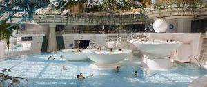 La piscina cubierta de Caldea + Naturlandia en Andorra permite a los bañistas disfrutar de grandes estructuras de cuencos blancos y de una exuberante vegetación. - ForTwo - Planes para parejas