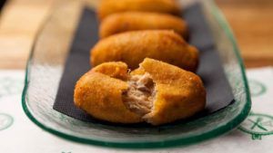 Primer plano de cuatro croquetas en un plato de cristal en el Restaurante Bache San Pedro (Sevilla), con una de ellas rota para mostrar su delicioso relleno. - ForTwo - Planes para parejas