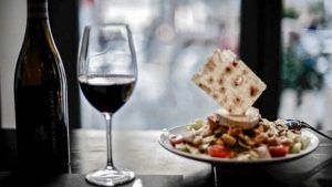 Una copa de vino tinto acompaña una ensalada con una galleta waffle en el Restaurante L'expérience de Málaga, elegantemente situado en una mesa junto a la ventana. - ForTwo - Planes para parejas