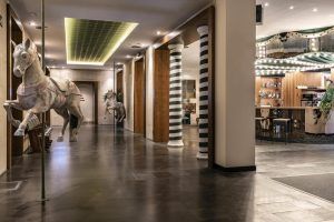 En el Hotel Vincci Soho de Madrid, un pasillo decorado con motivos de caballos de carrusel y columnas rayadas conduce a un acogedor bar. - ForTwo - Planes para parejas