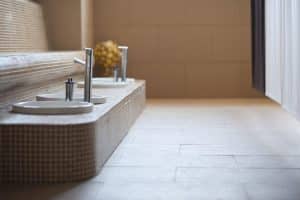 Este baño minimalista, que refleja el ambiente sereno del Circuito Termal 90 minutos en Kumaras Spa (Umbrete), exhibe dos lavabos redondos con grifos modernos contra pisos y paredes de baldosas beige, lo que ofrece un escape tranquilo. - ForTwo - Planes para parejas