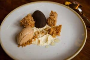 Un postre plato con mousse cremosa, trozos de bizcocho, avellanas y delicados porciones se presenta con arte en el Restaurante Dos Cielos (Madrid). - ForTwo - Planes para parejas