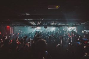 En City Hall Barcelona, una vibrante discoteca, la gente baila con las manos en alto bajo luces tenues, haciendo eco de la enérgica vida nocturna. - ForTwo - Planes para parejas