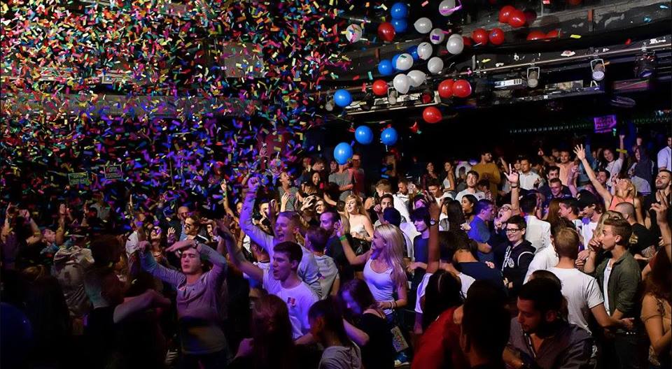 El ambiente animado de una celebración en el Ayuntamiento de Barcelona se captura con confeti y globos de colores mientras la gente baila y disfruta de cada momento vibrante juntos. - ForTwo - Planes para parejas