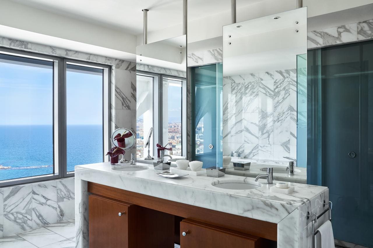 Disfrute de un lujoso baño de mármol en el Hotel Arts de Barcelona, con vistas al mar, lavabos dobles, un gran espejo, armarios de madera y accesorios modernos. - ForTwo - Planes para parejas